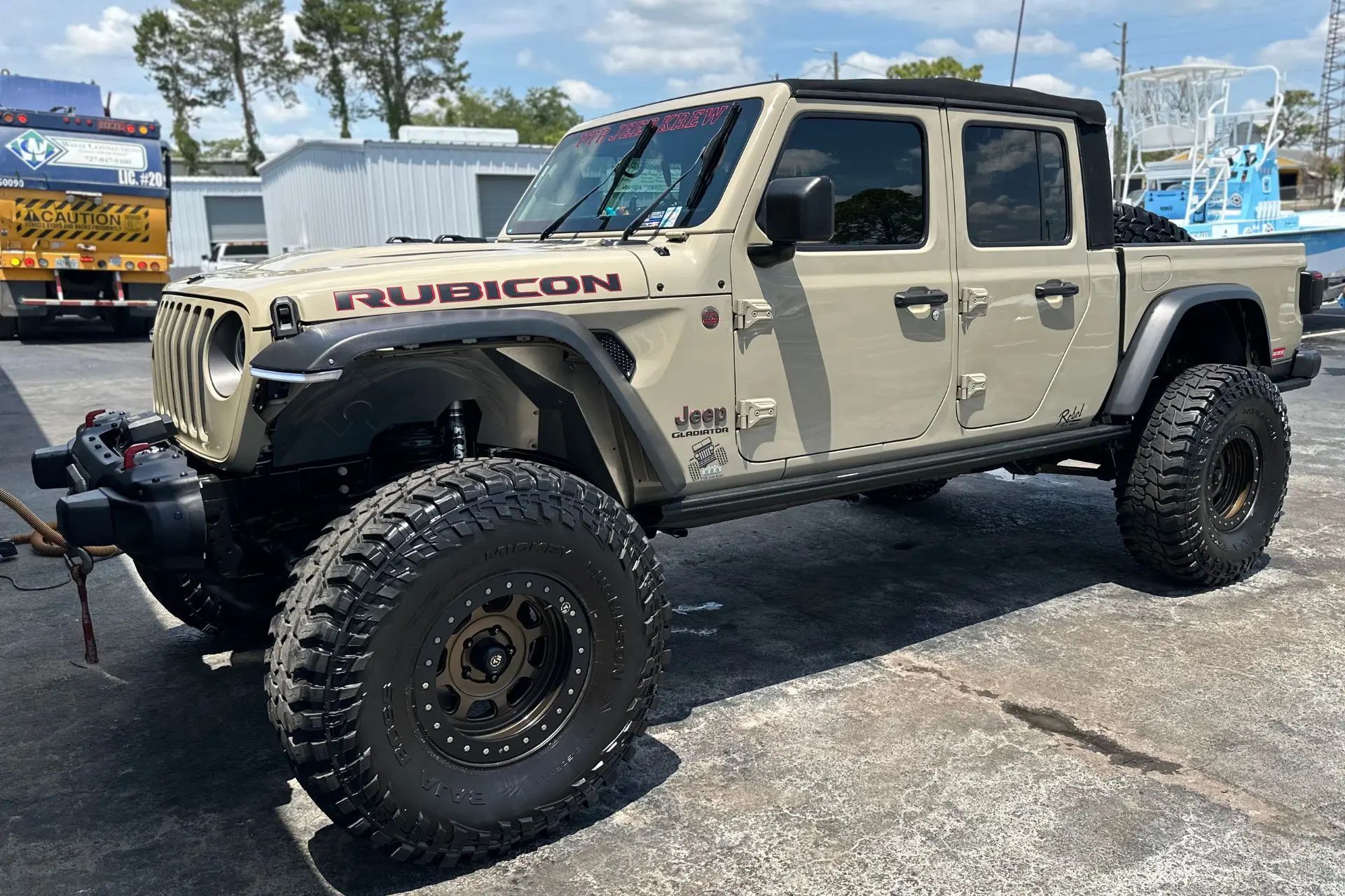 A jeep gladiator is parked in a parking lot.