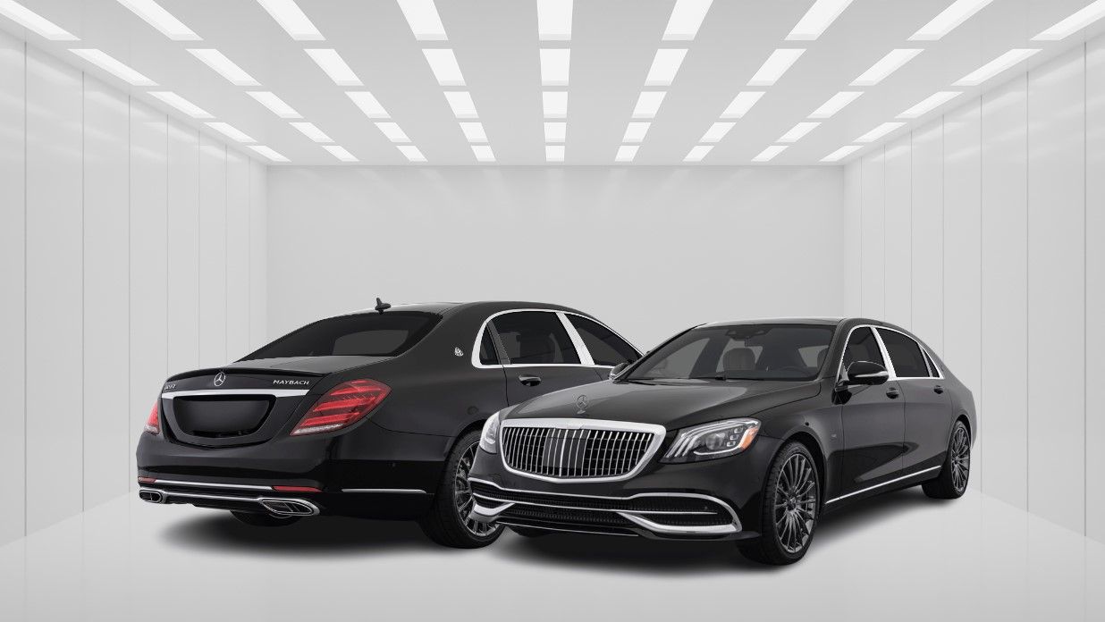 Two black mercedes benz cars are parked next to each other in a room.