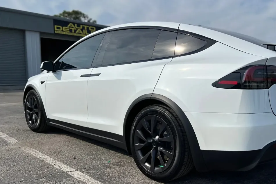 A white tesla model x is parked in a parking lot.
