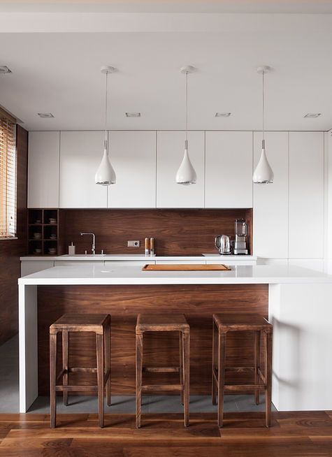 A kitchen with white cabinets and wooden stools
