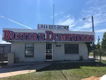 A white building with a sign that says buster 's dumpsters on it.