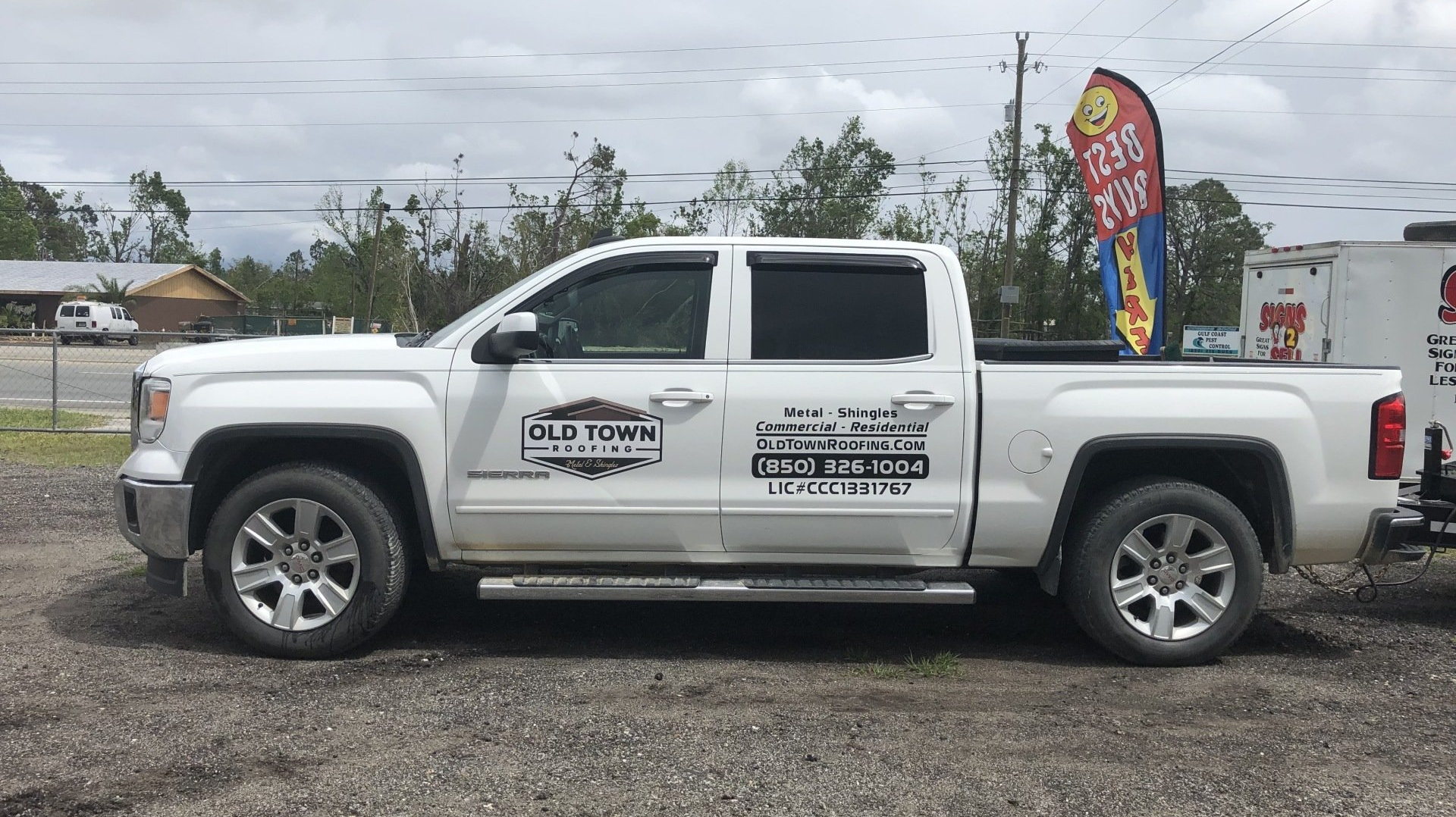 A white truck is parked in a gravel lot.