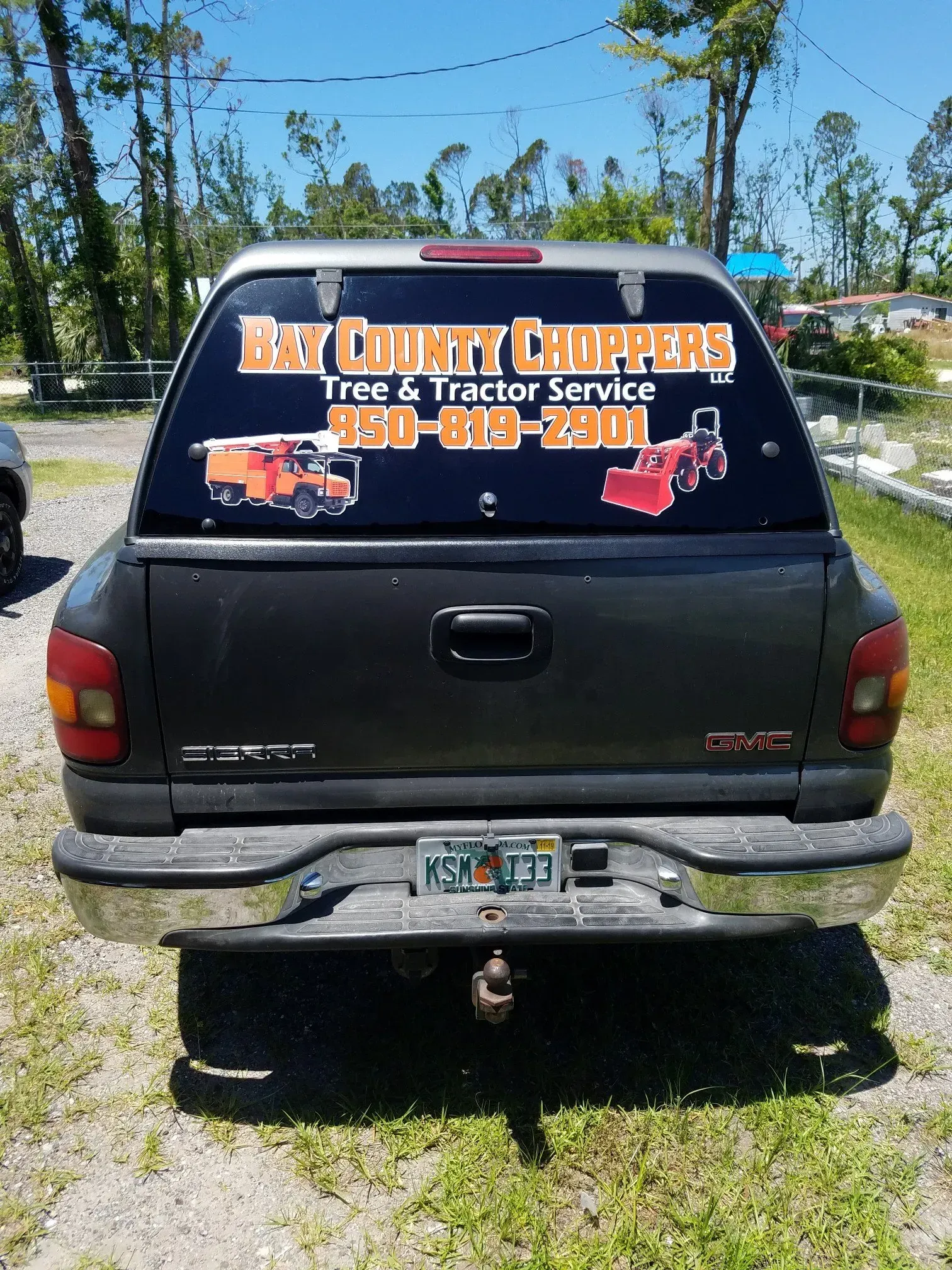 A gmc truck with a sticker on the back window that says bay country chopper tree and tractor service