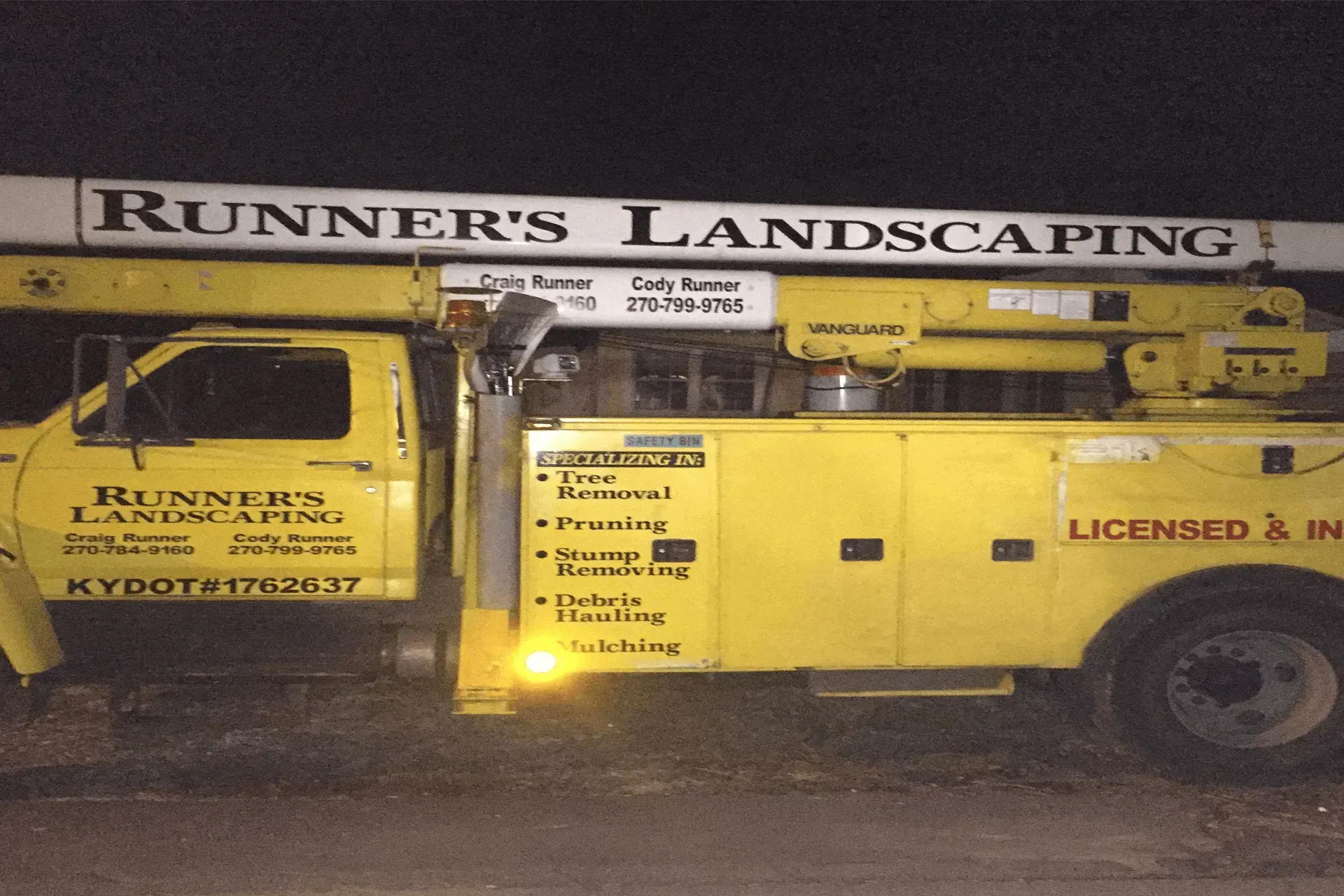 A yellow runner 's landscaping truck is parked in front of a building