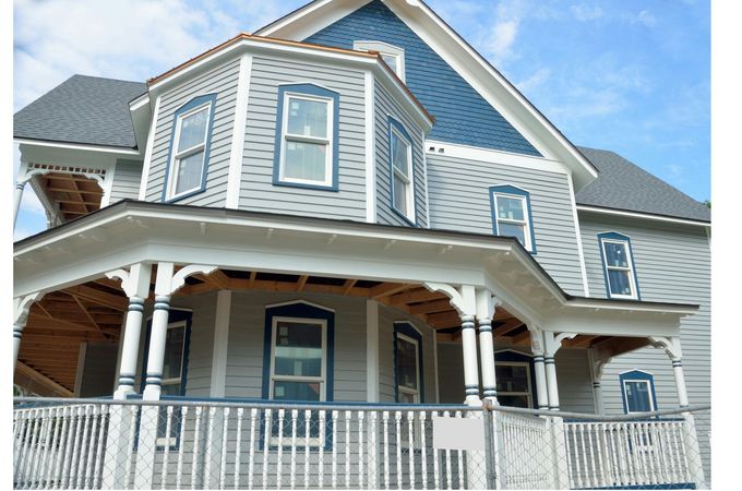 A large house with a large porch is under construction.