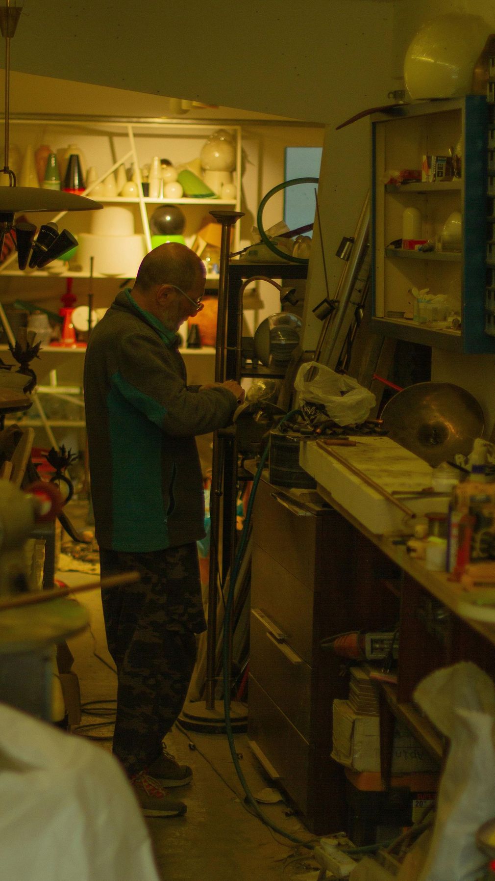 A man is working on a machine in a messy room.