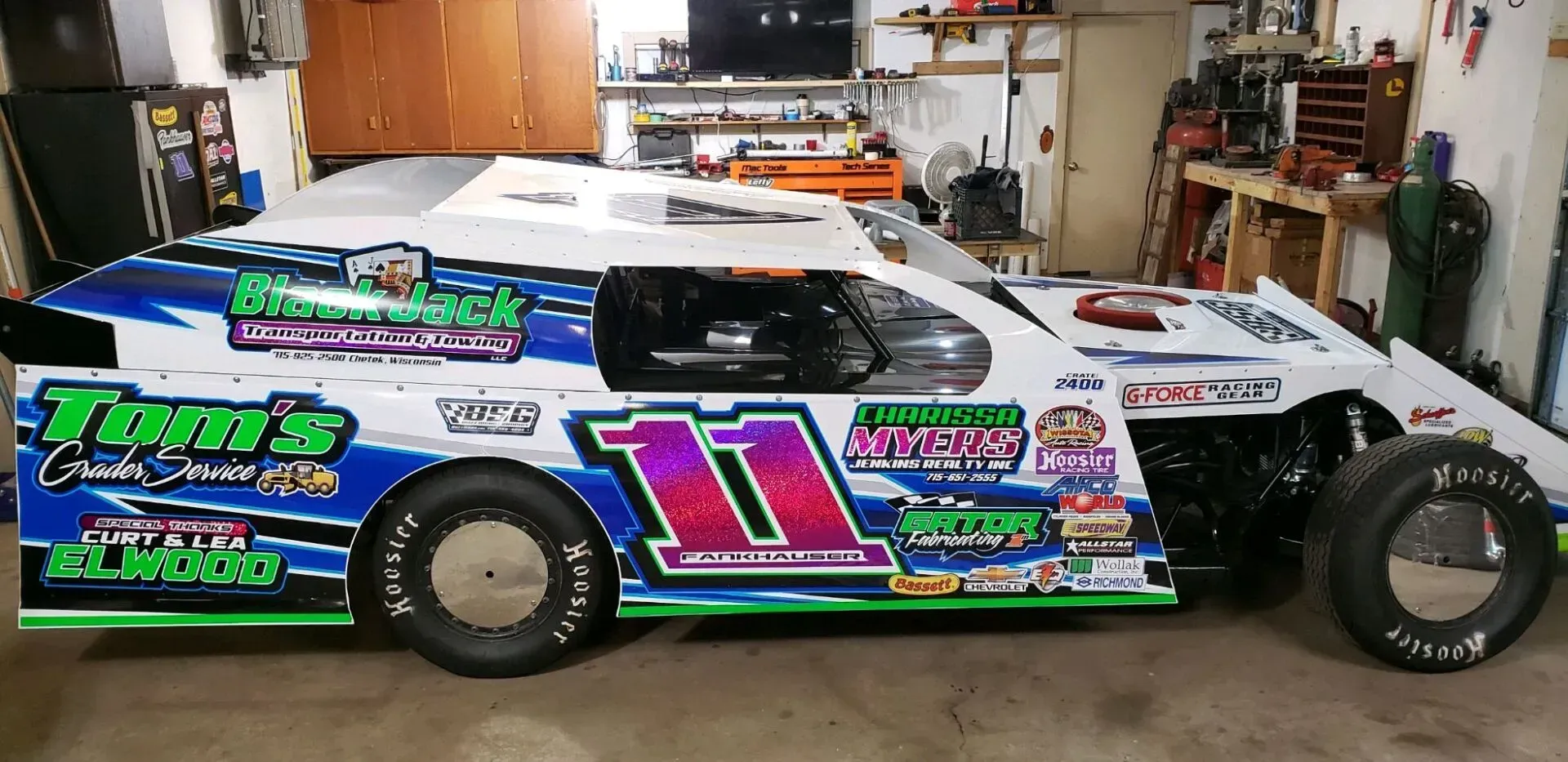 A race car is parked in a garage with the number 11 on it.