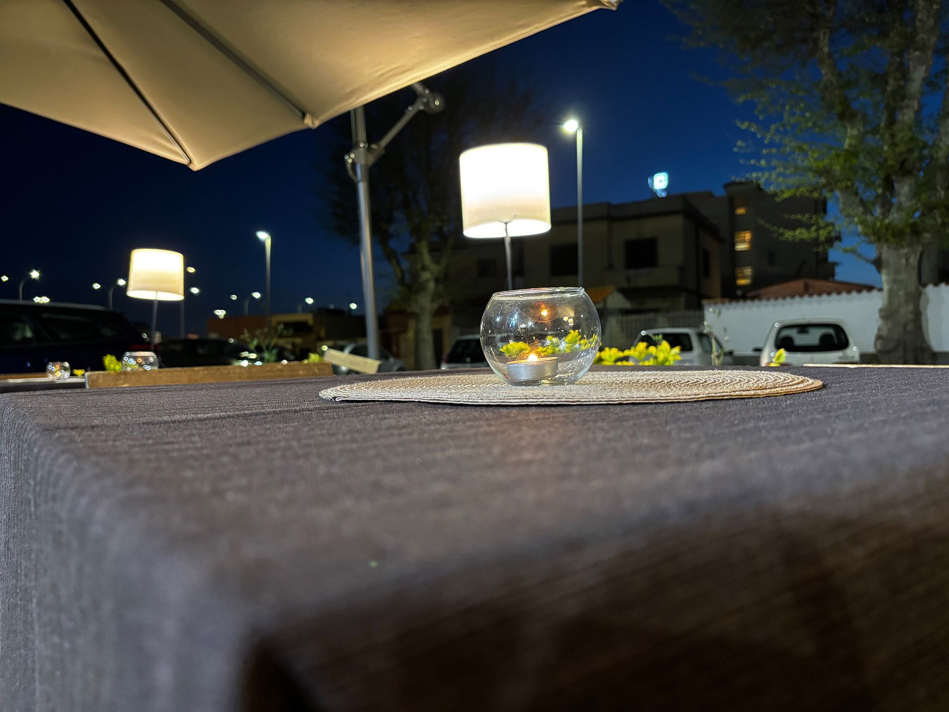 Un tavolo con un vaso di fiori sopra sotto un ombrellone di notte