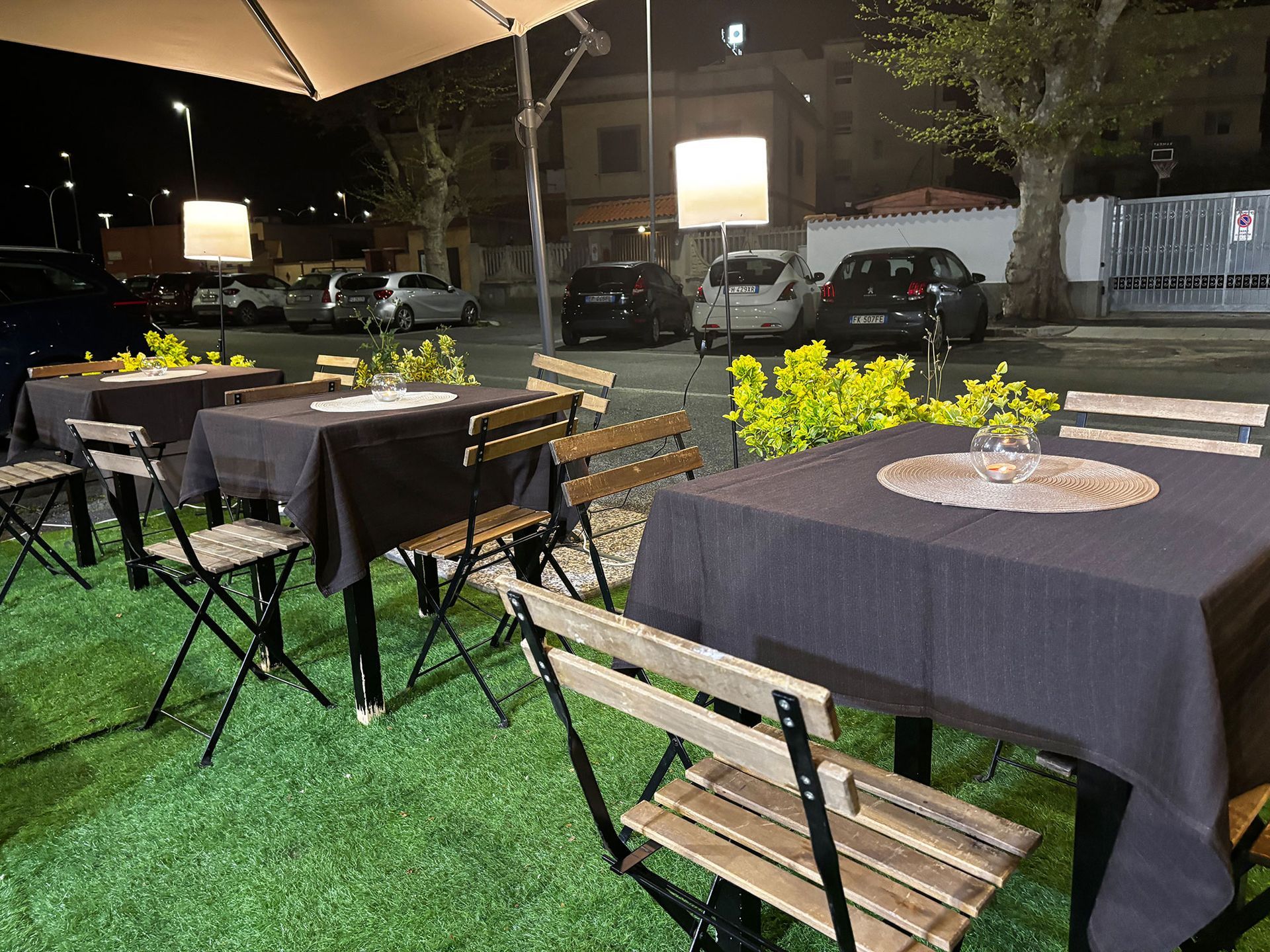 Una fila di tavoli e sedie in un parcheggio di notte