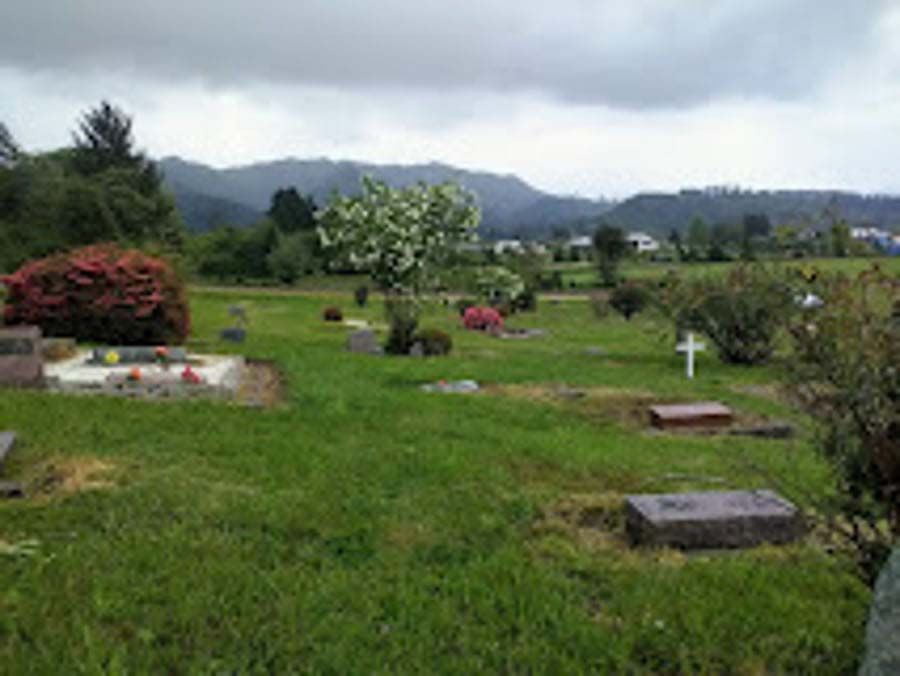 A cemetery with mountains in the background on a cloudy day.