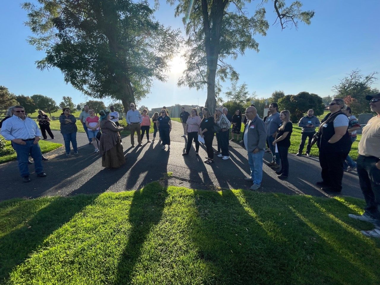 A group of people are standing in a circle in the grass.