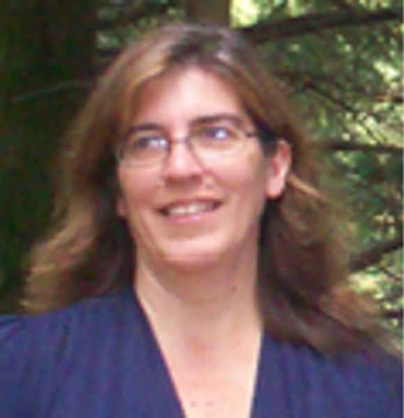 A woman wearing glasses and a blue shirt smiles for the camera