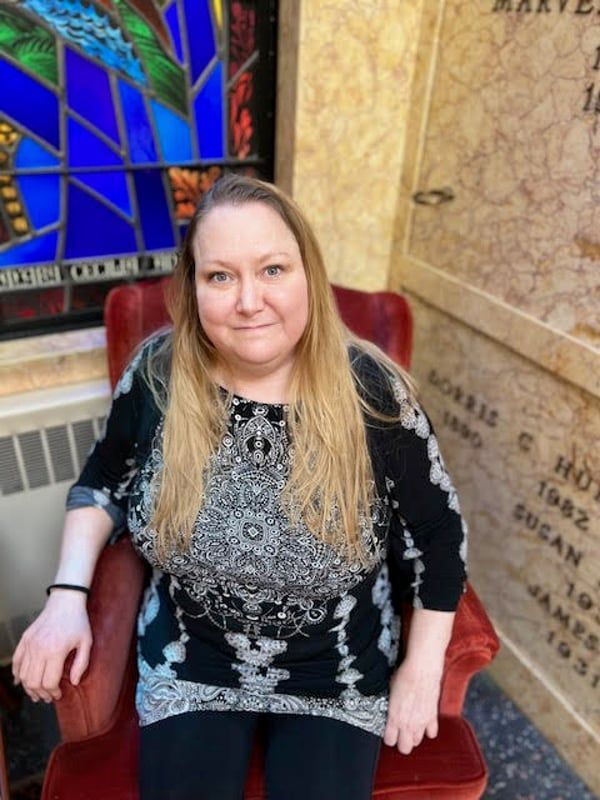 A woman is sitting in a chair in front of a stained glass window