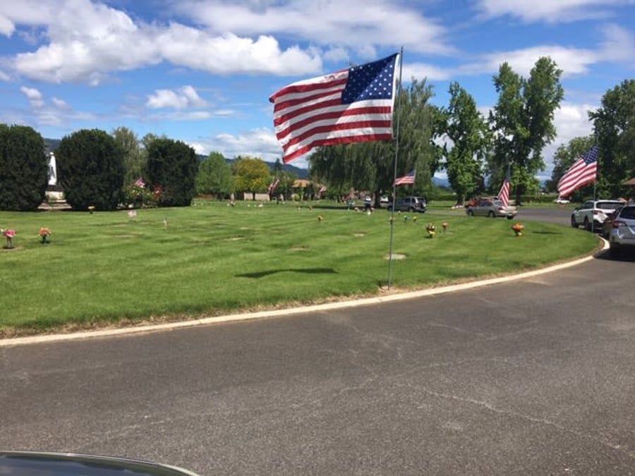 A large american flag is flying in a cemetery