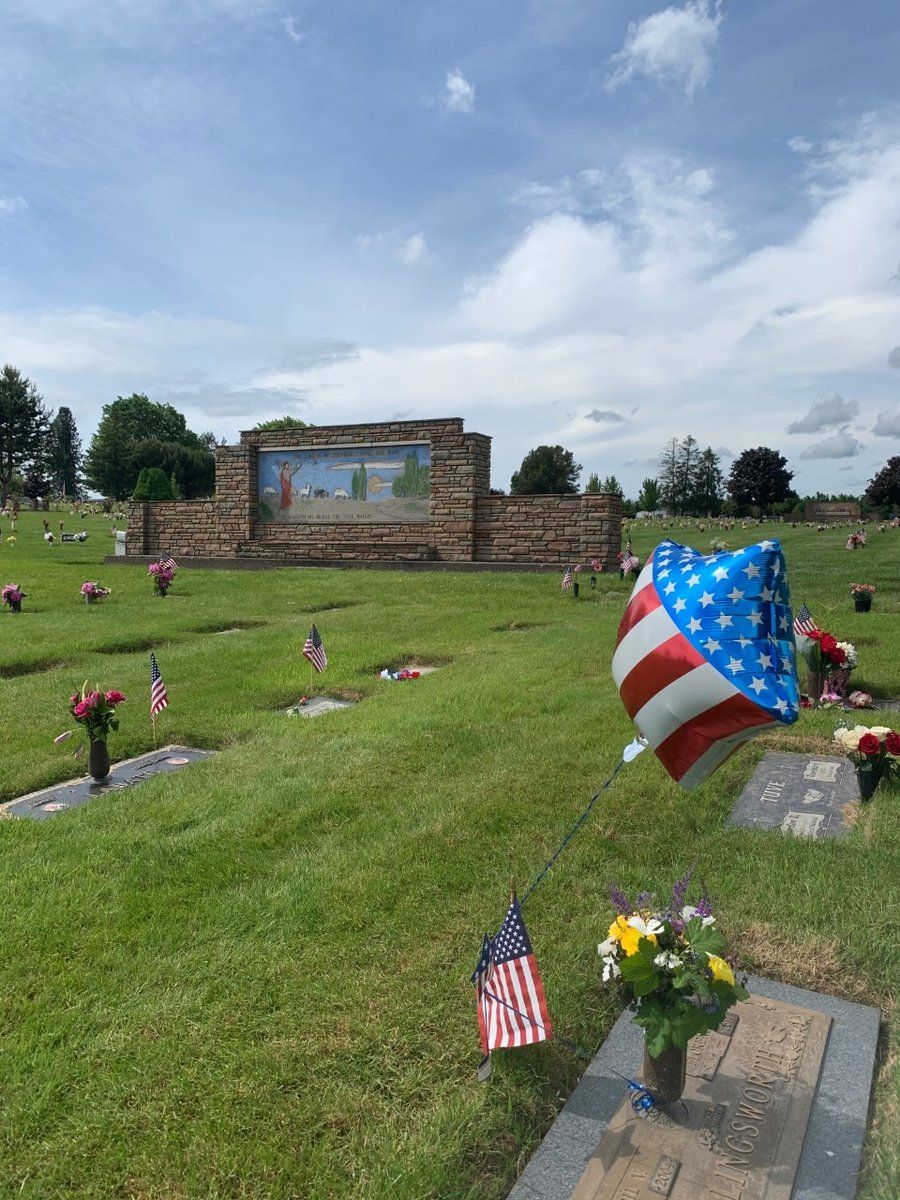 A cemetery with a balloon in the shape of an american flag.