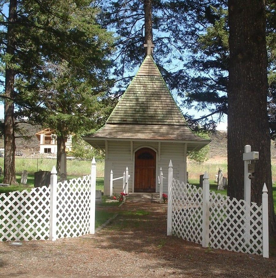 A small white building with a cross on top of it