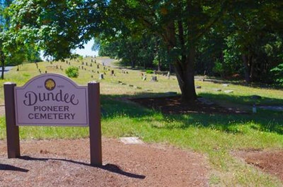 A sign for dundee pioneer cemetery is in front of a cemetery.