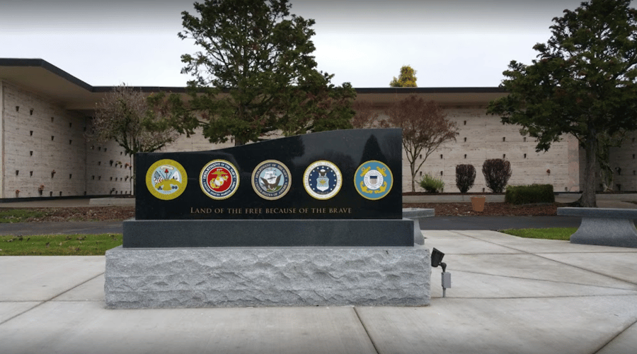 A memorial with military emblems on it in front of a building