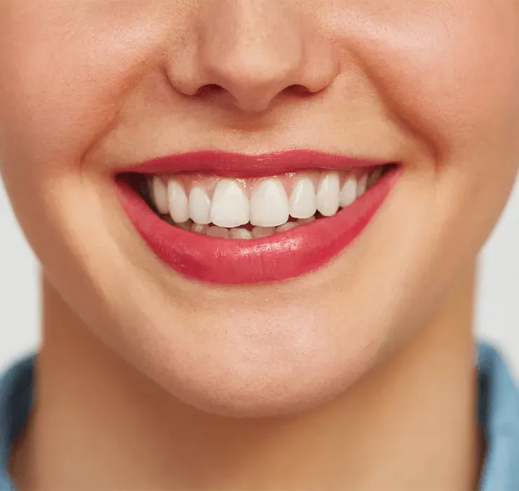 A close up of a woman 's smile with white teeth and red lipstick.