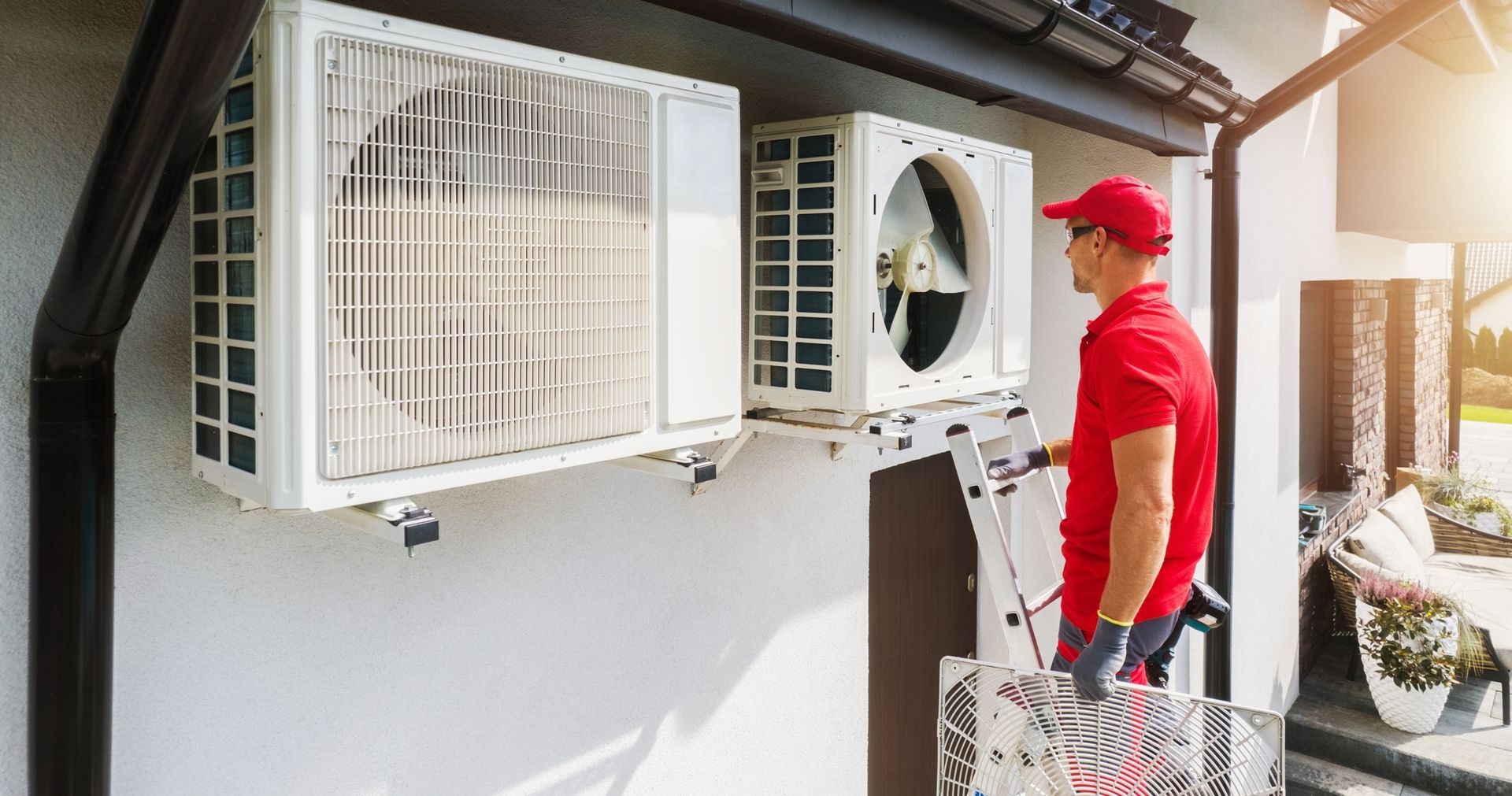 A man is installing an air conditioner on the side of a building.