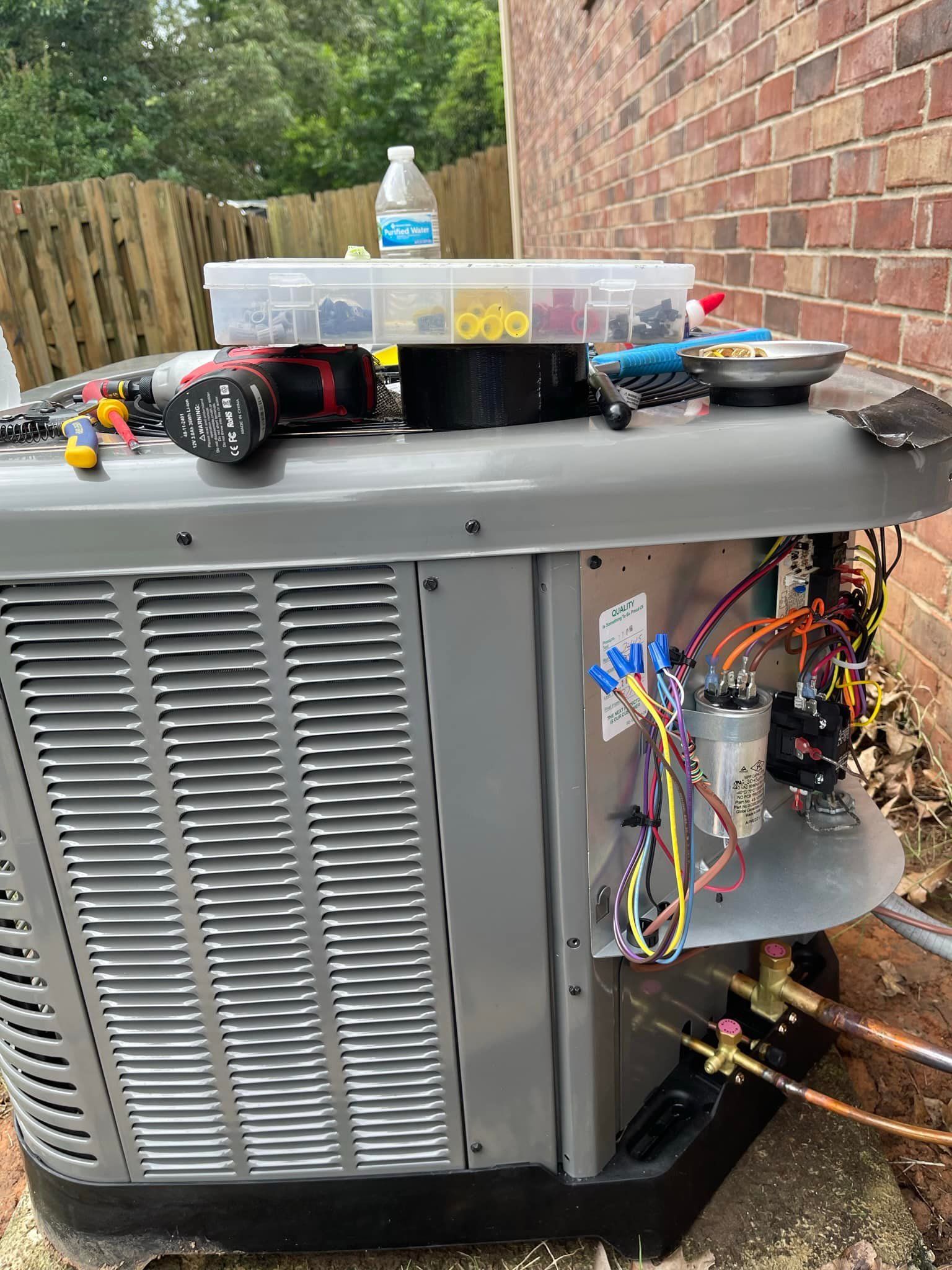 A large air conditioner is sitting on top of a brick wall.