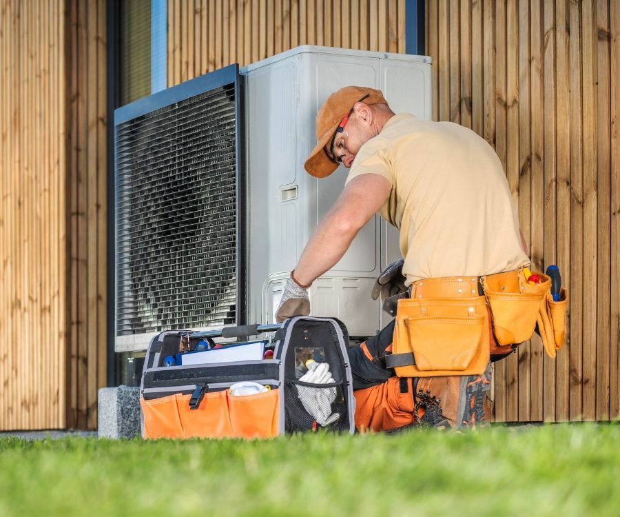 A man is working on an air conditioner outside of a house.
