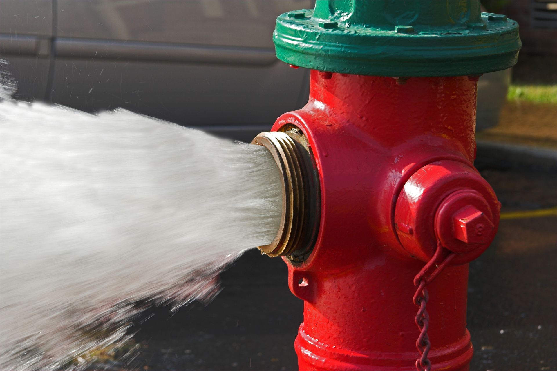Water is expelled at a high velocity from a red fire hydrant.