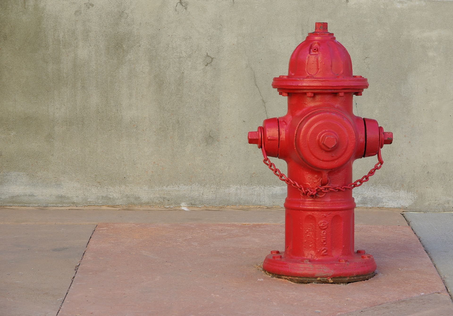 A red fire hydrant is on a lone street.