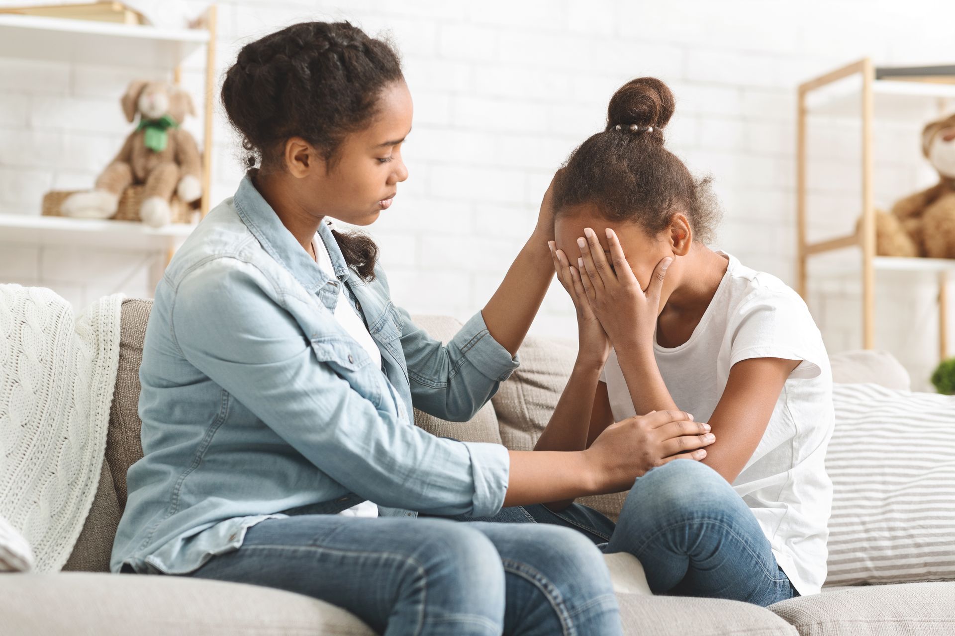 A woman is sitting on a couch talking to a little girl.