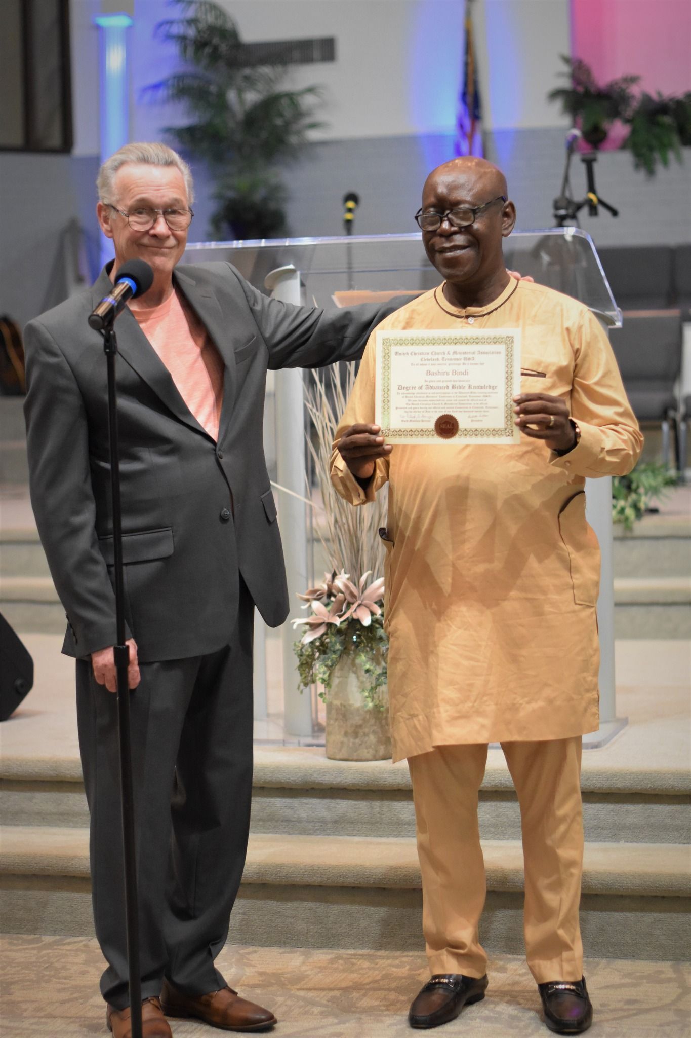 Two men are standing next to each other and one is holding a certificate.