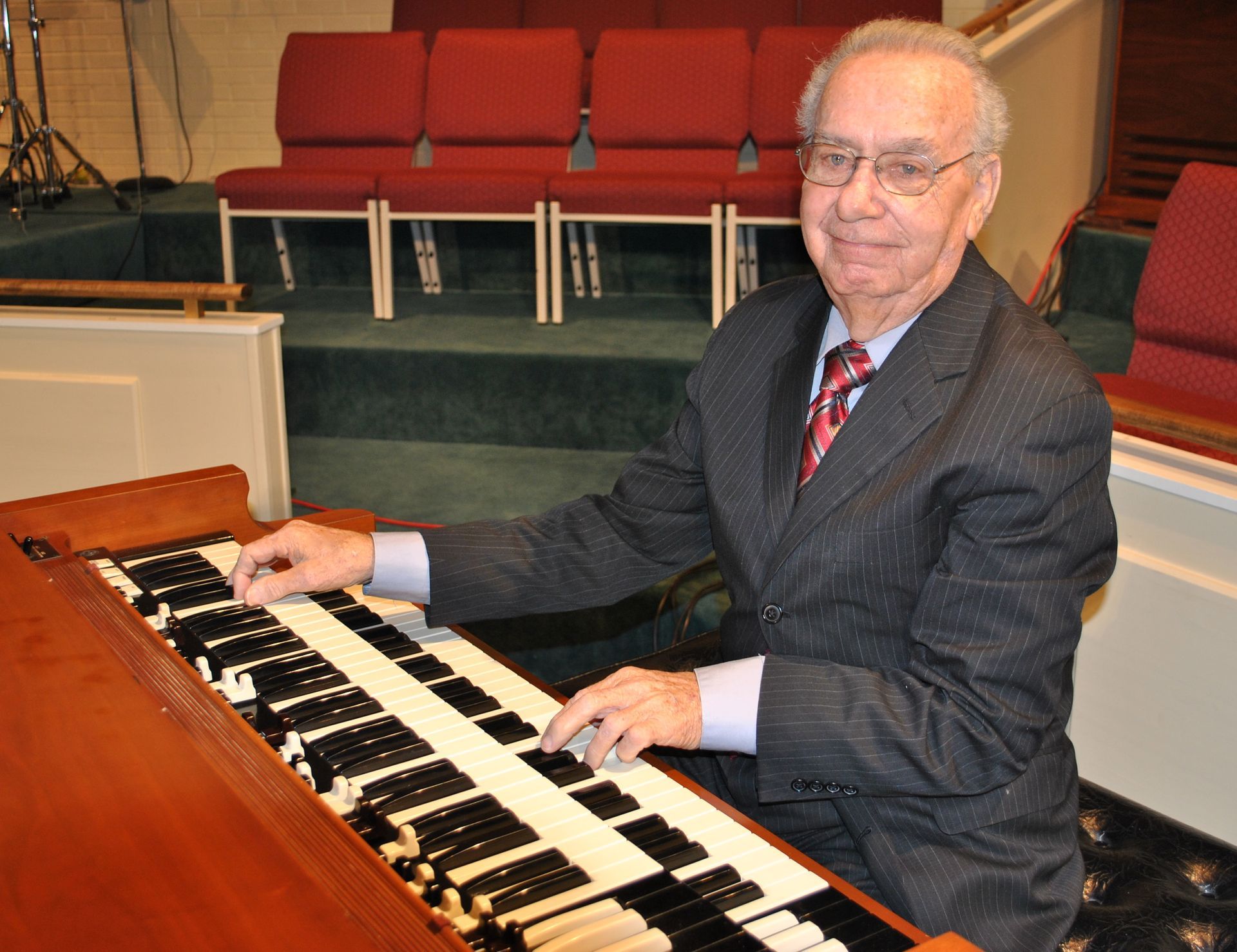 A man in a suit and tie is playing an organ