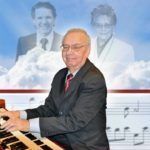 A man in a suit and tie is playing an organ.