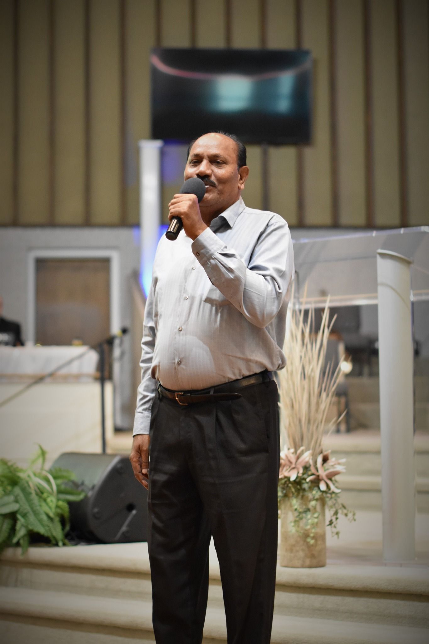 A man is standing in front of a microphone in a church.