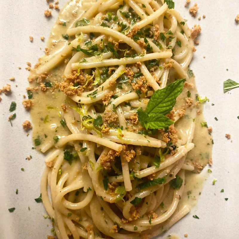 Piatto di pasta con sugo, erbe aromatiche e pangrattato, guarnito con menta.