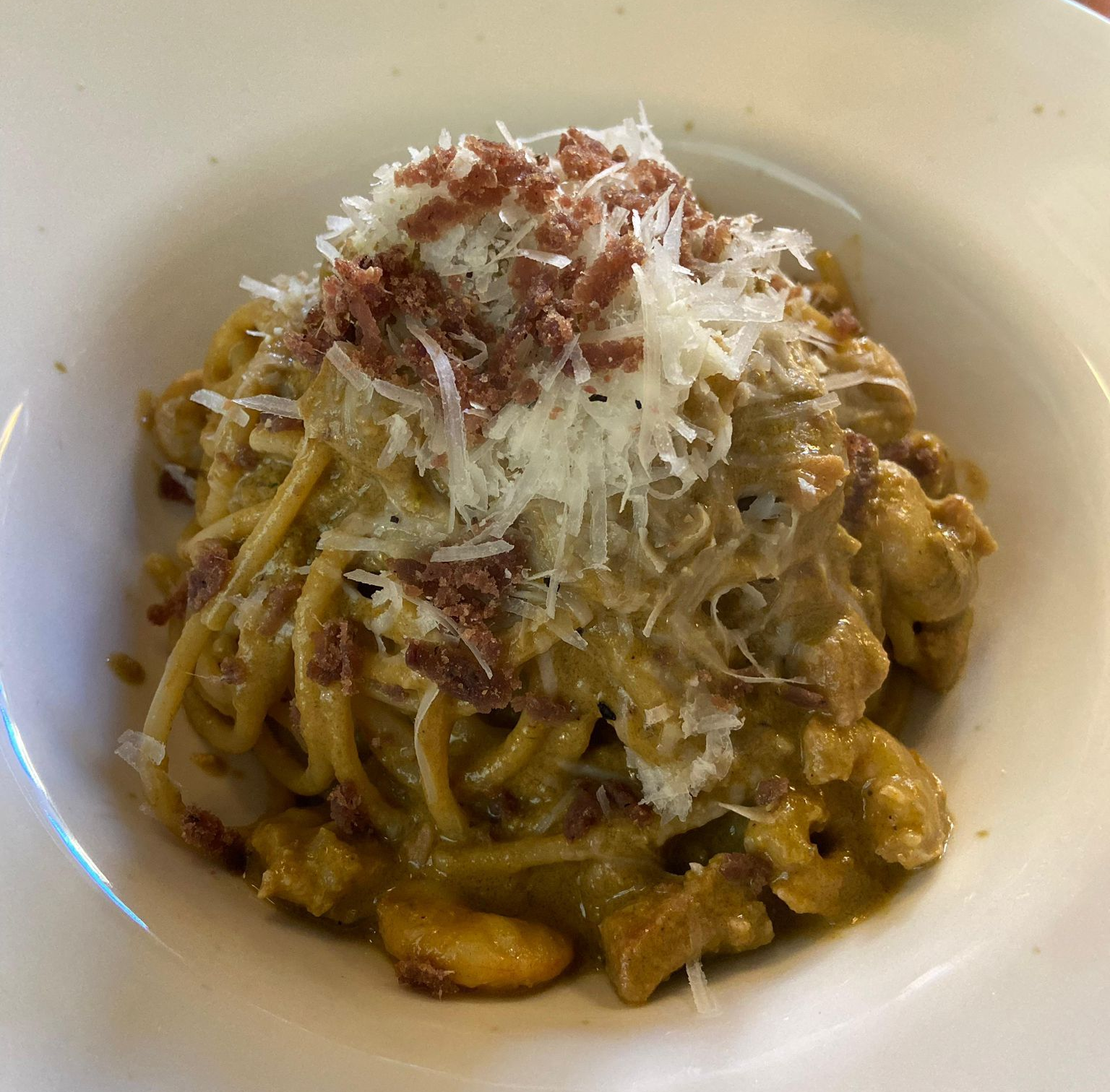 Piatto di frutti di mare: gamberi, carpaccio di pesce e tartare di tonno su un piatto blu.