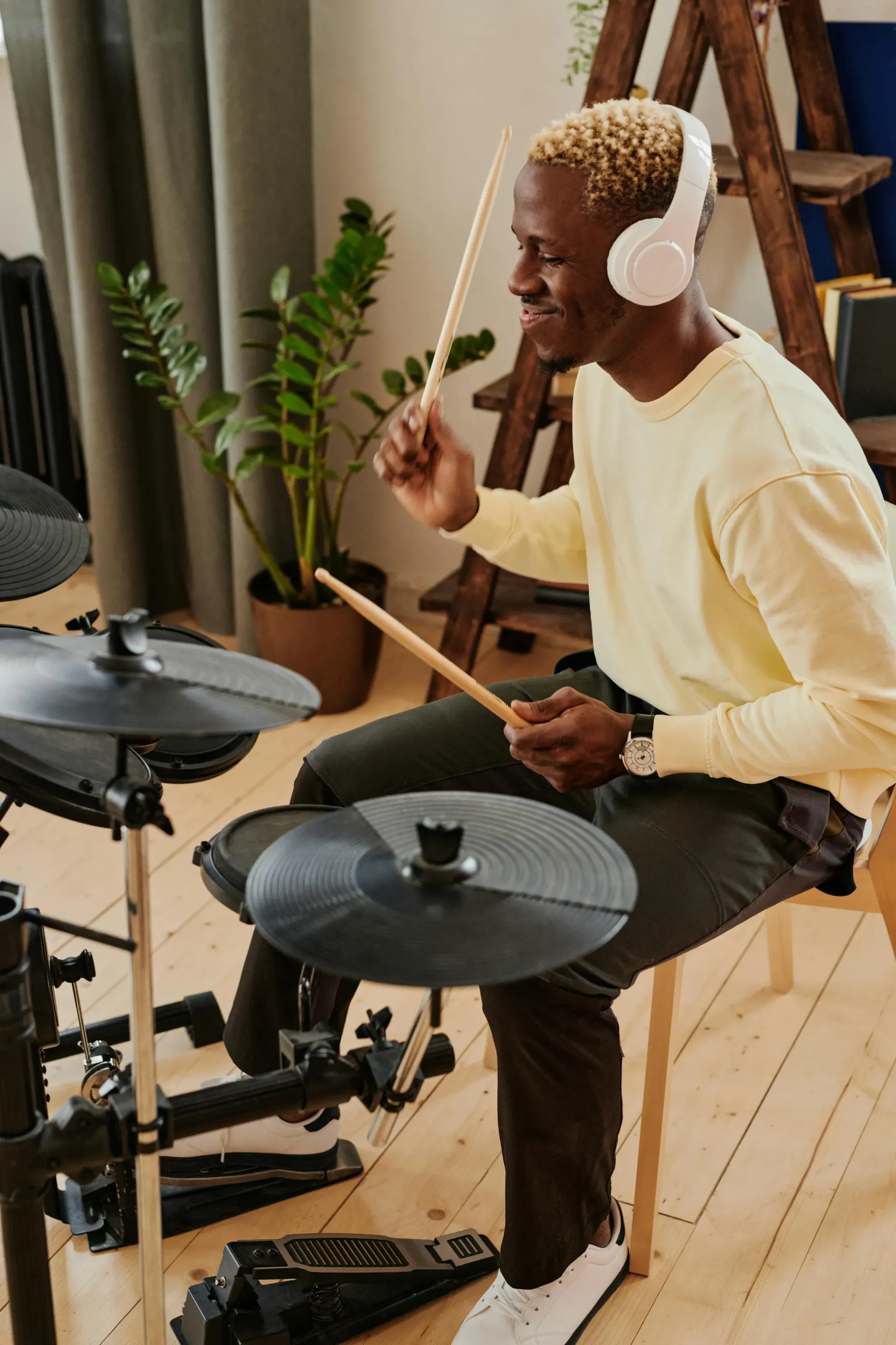 A person wearing headphones plays a digital drum set.
