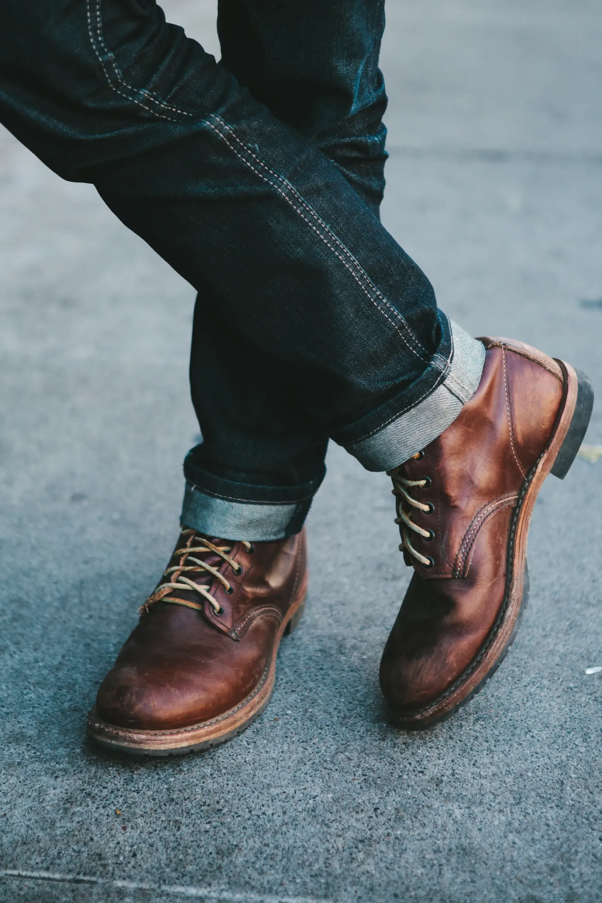 Person wearing dark wash jeans and brown leather boots.