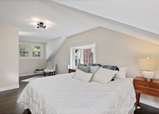 A bedroom with a bed , nightstand , chair and window.