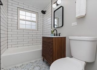 A bathroom with a toilet , sink , tub and mirror.