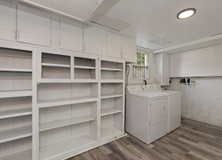 A laundry room with a washer and dryer and shelves.