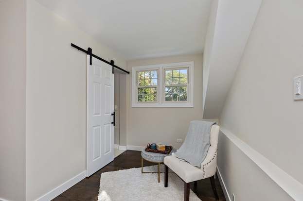A living room with a chair , table and sliding barn door.