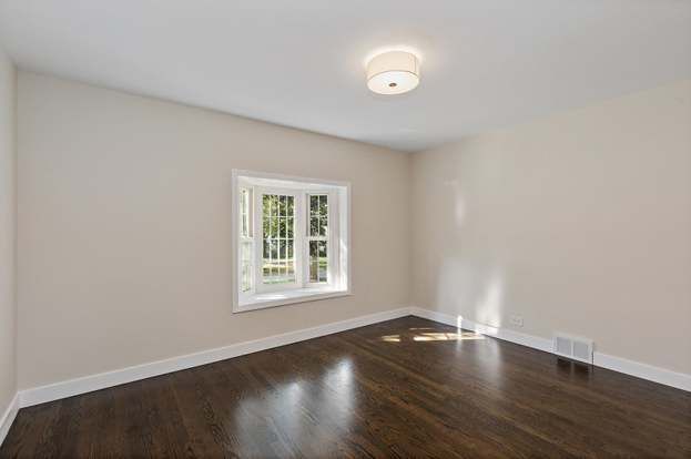 An empty room with hardwood floors and a window.