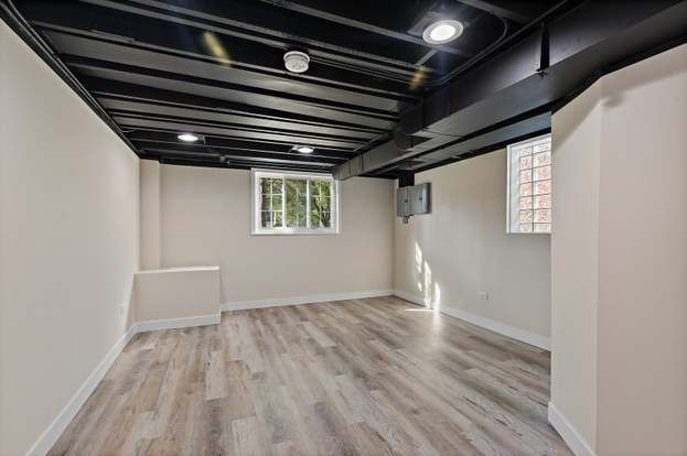 An empty basement with hardwood floors and a window.
