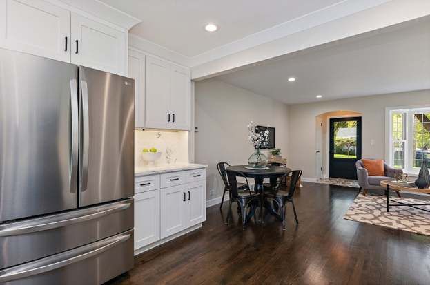 A kitchen with stainless steel appliances , white cabinets and hardwood floors.