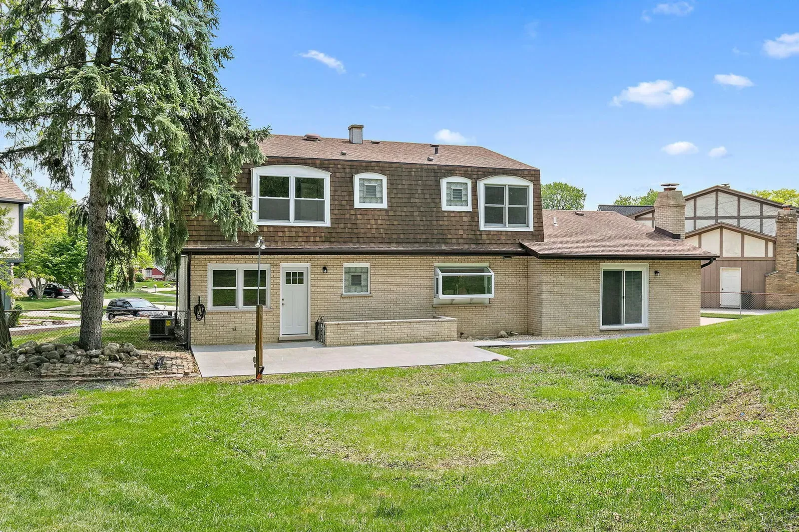 A large house with a lot of windows is sitting on top of a lush green field.
