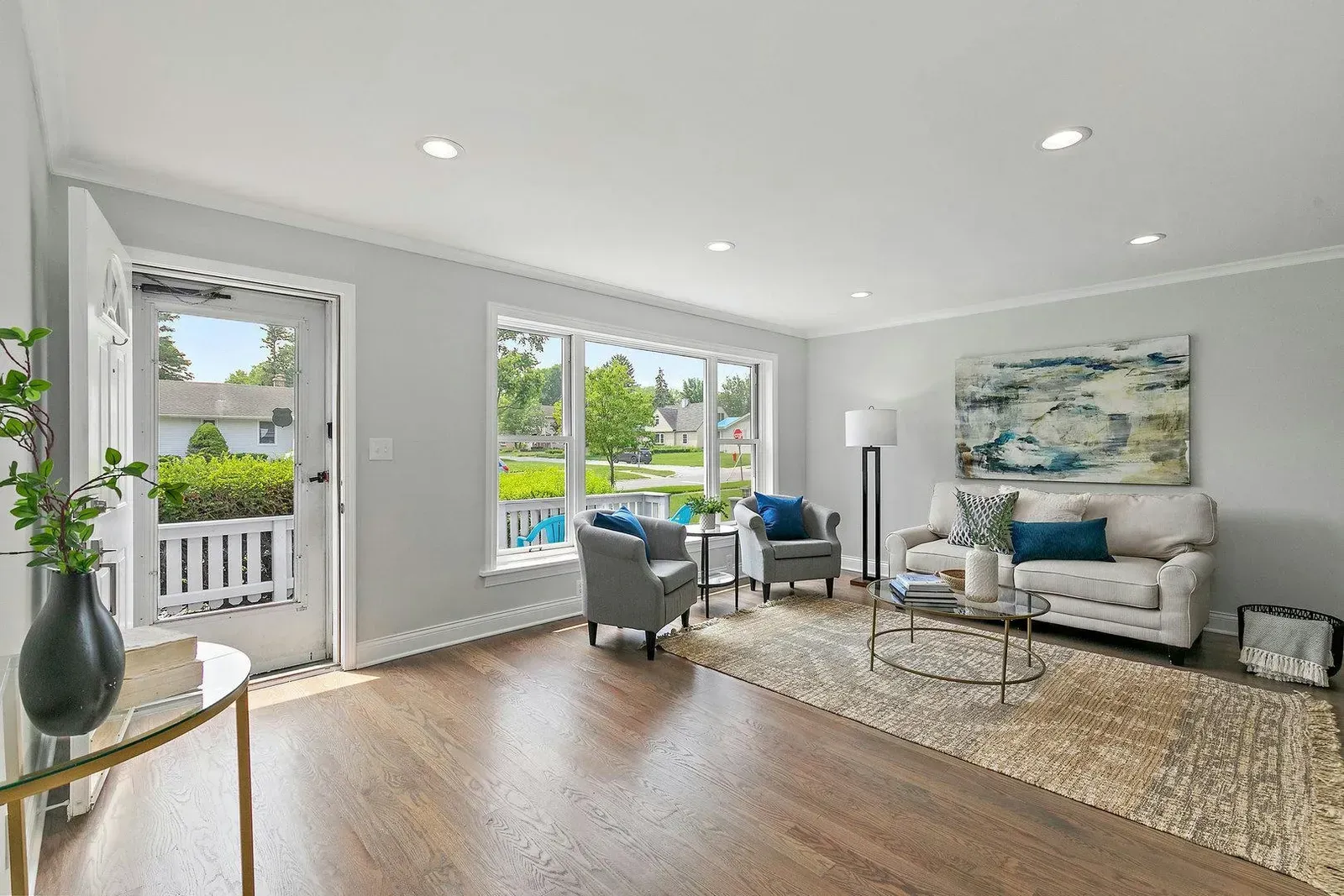 A living room with a couch , chairs , tables and a large window.