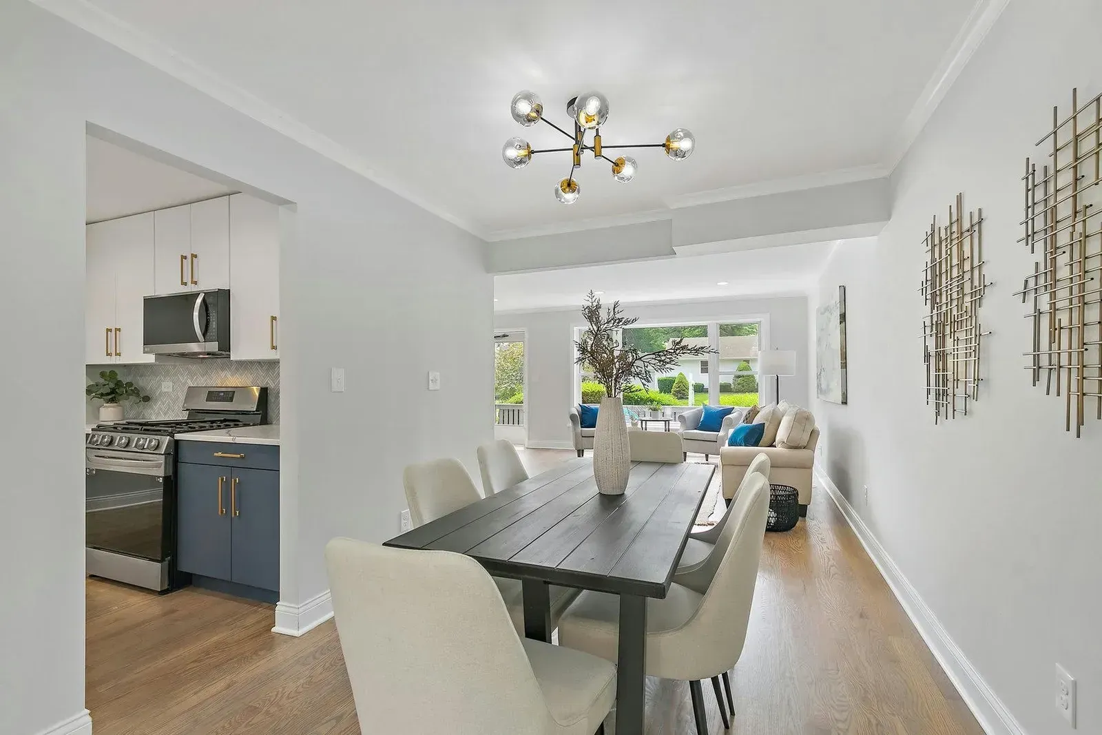 A dining room with a table and chairs and a kitchen in the background.