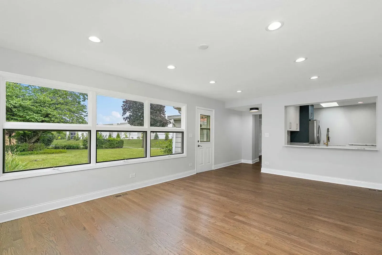 An empty living room with hardwood floors and lots of windows.