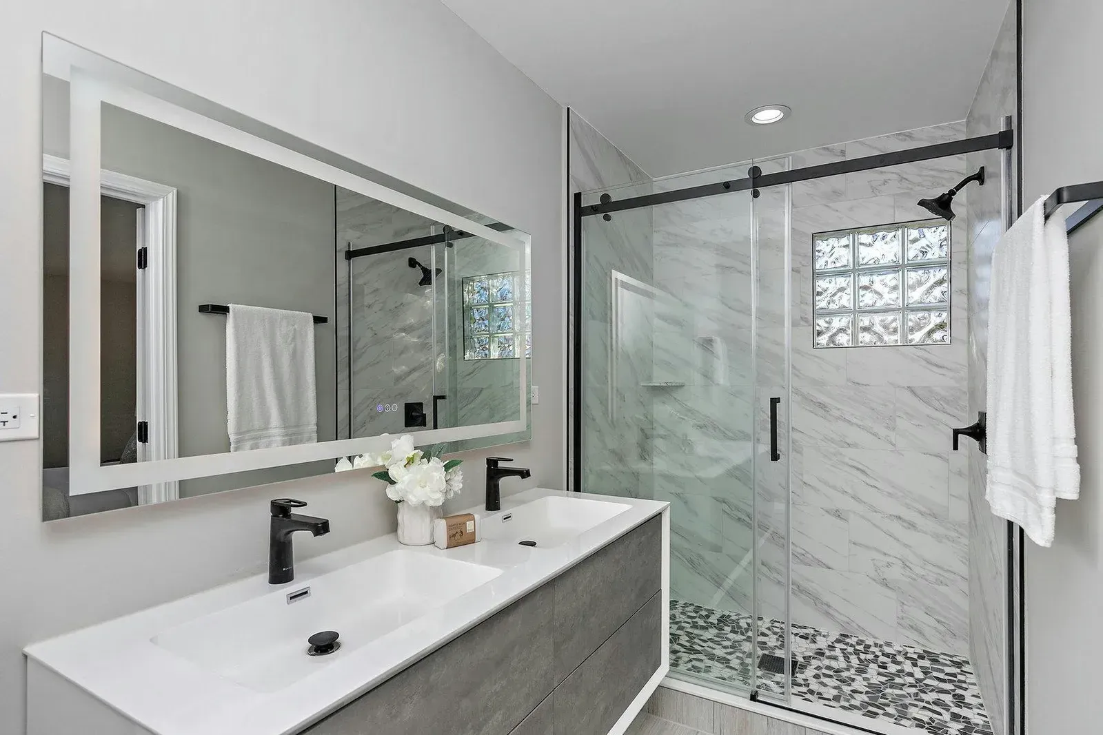 A bathroom with a double sink and a walk in shower.