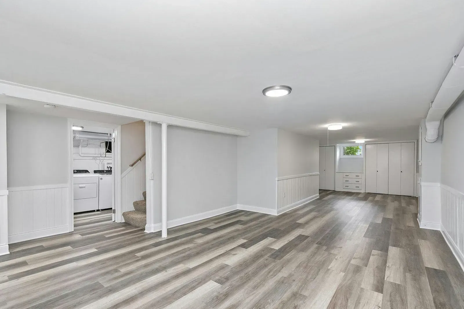 A large empty basement with hardwood floors and white walls.